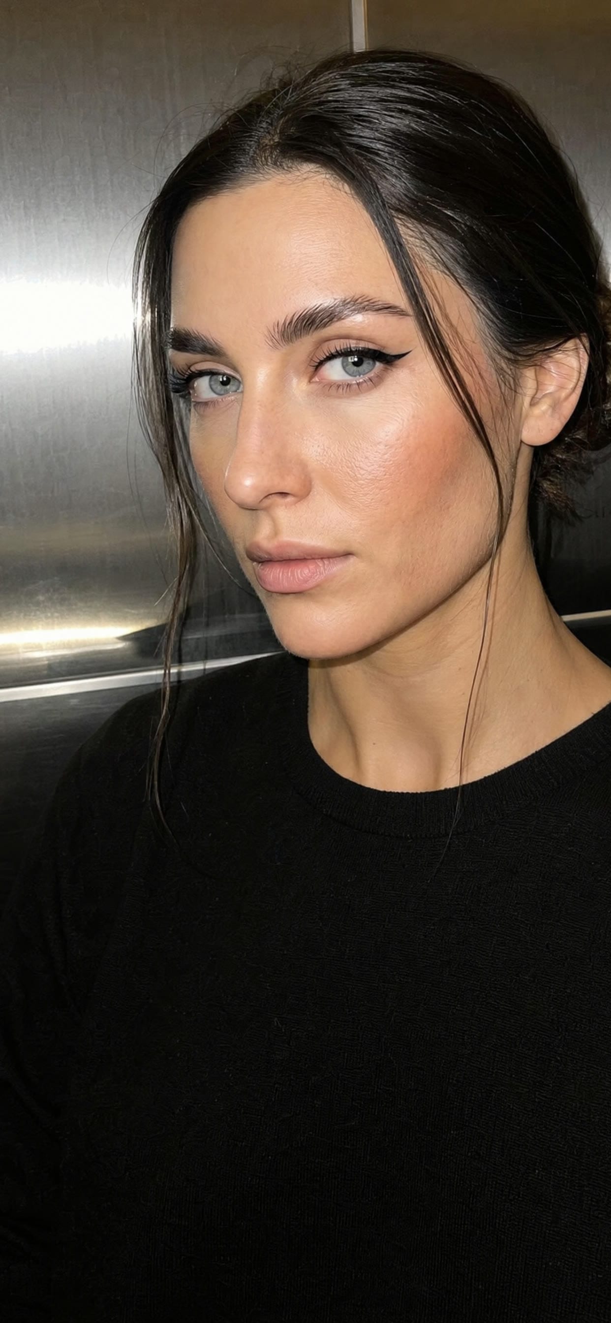 Permanent Eyeliner client in a steel elevator at night, lit by a phone flash