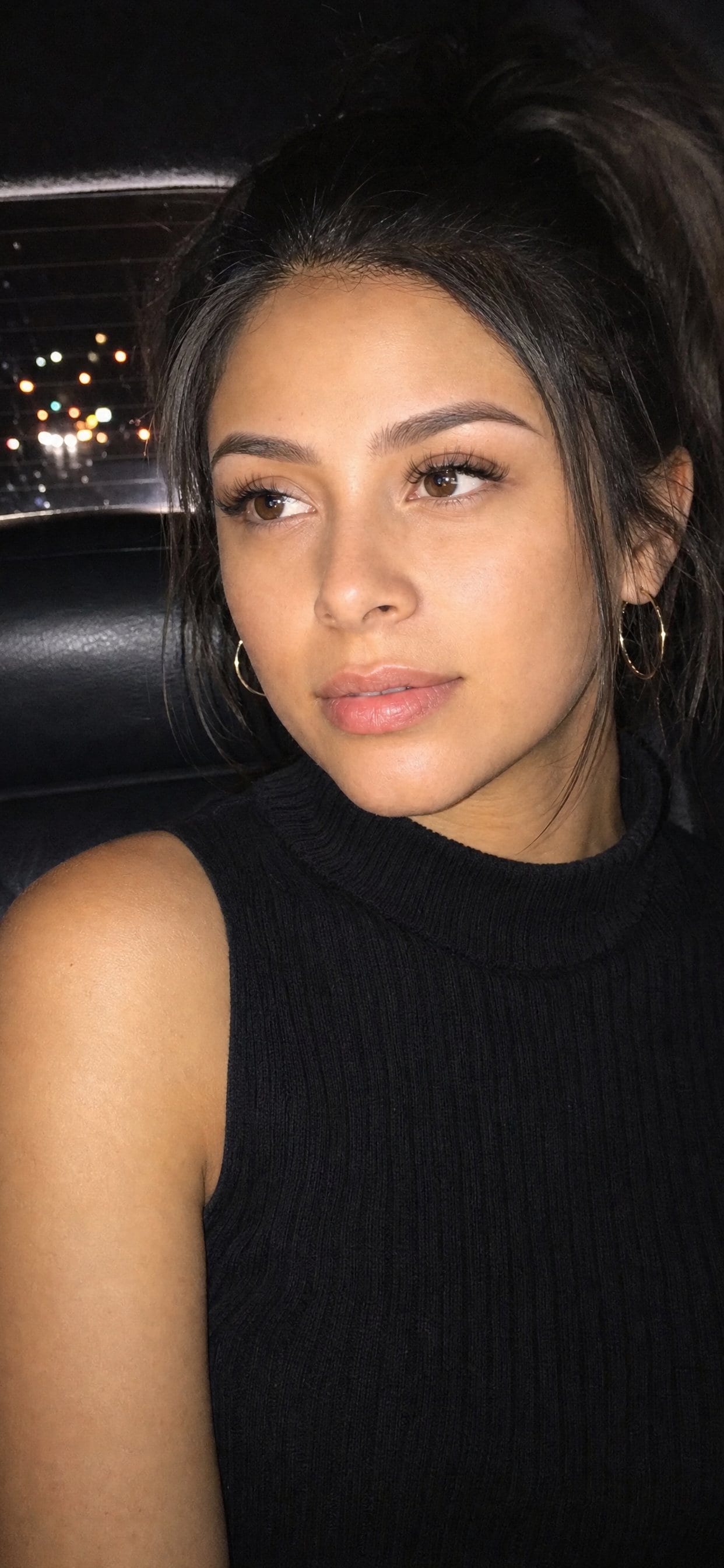 Powder Brows client in the back seat of a car at night, lit by a phone flash