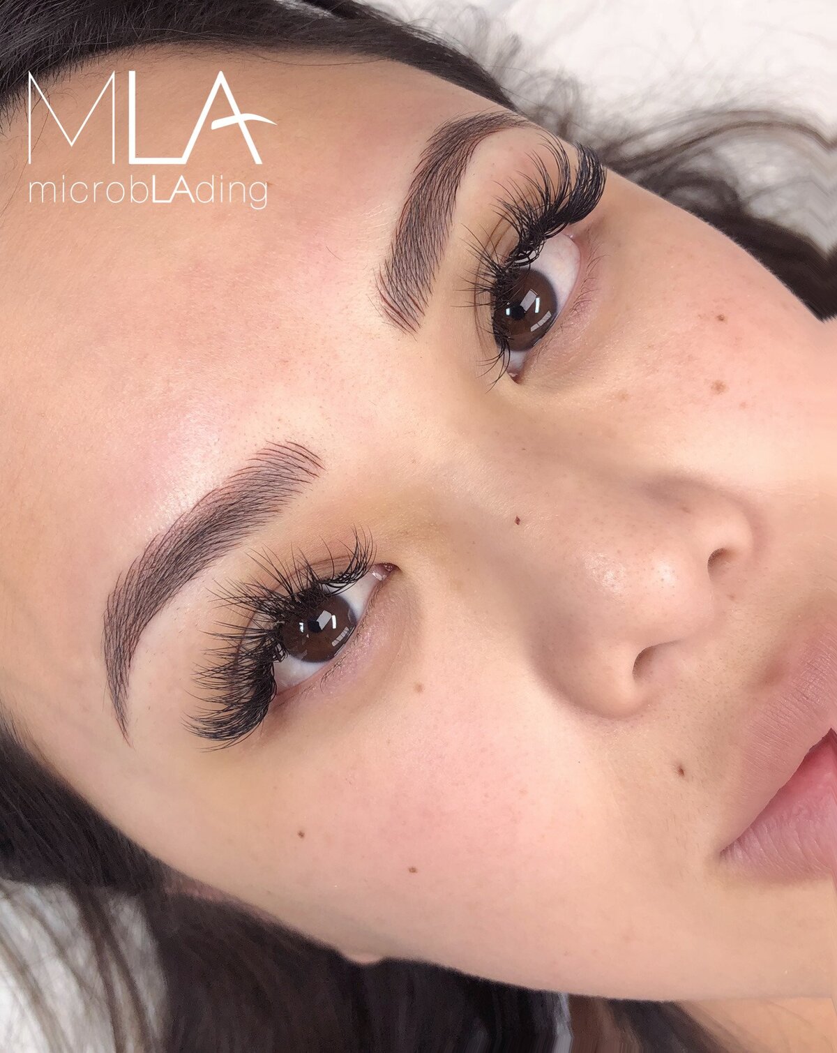 Nano brows results seen from above: fluffy dark brown hair strokes with a lifted arch, framed by long lashes, Microblading LA