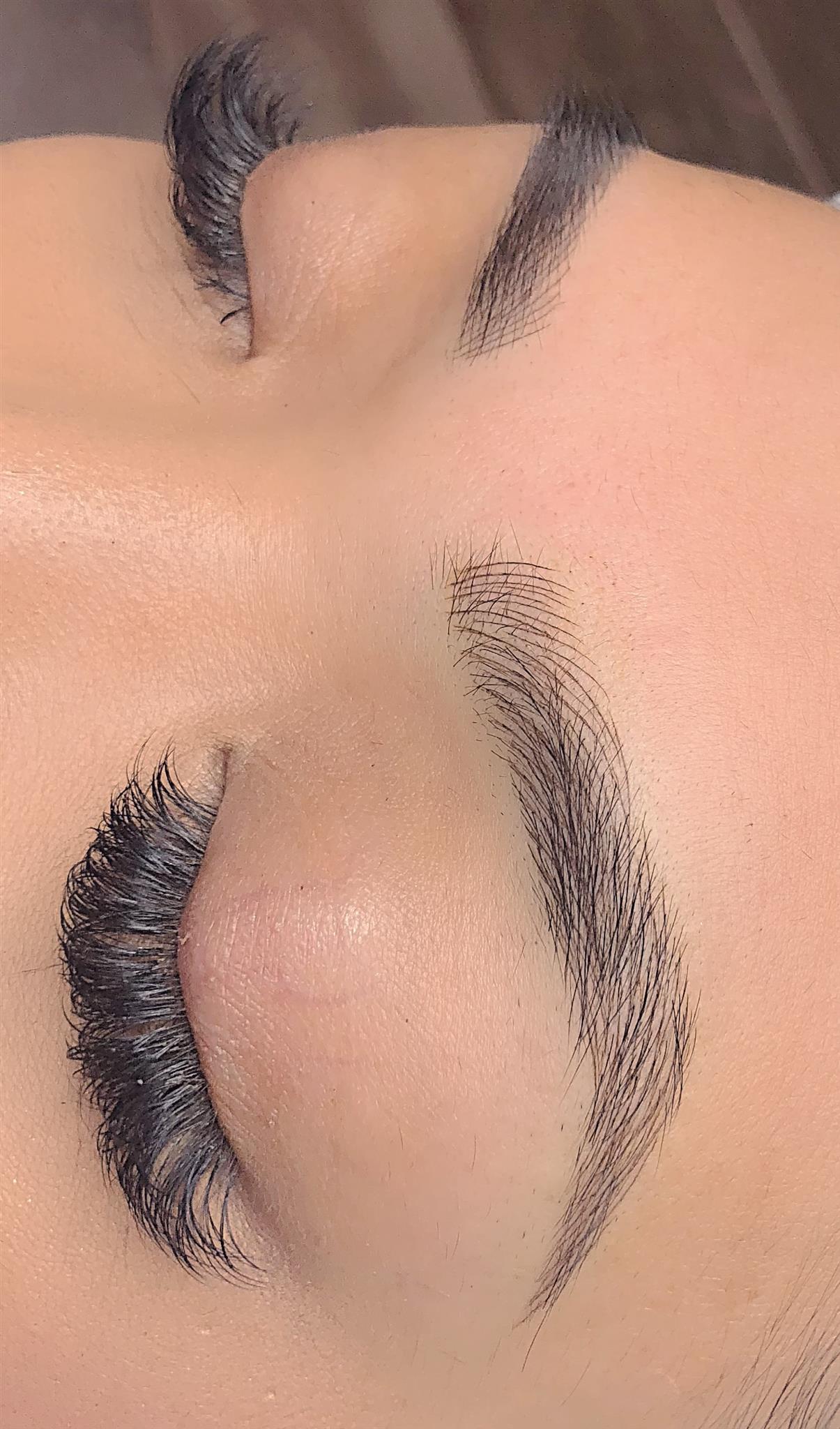 Nano brows close-up of one brow, eyes closed: fine, realistic dark brown hair strokes along a curved arch, Microblading LA