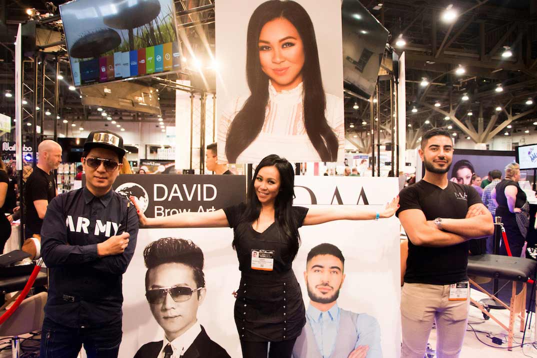 David Zhang Lindsey Ta and Rusen Donmez pose in front of their permanent makeup class signs